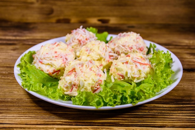 White plate with crabcheese balls and lettuce leaves on wooden table