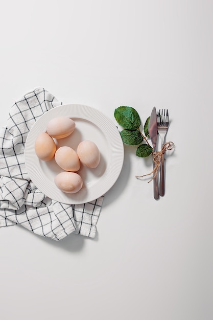 흰색 배경에 계란이 있는 흰색 접시 계란과 녹색 잎이 있는 접시가 있는 행복한 부활절 카드