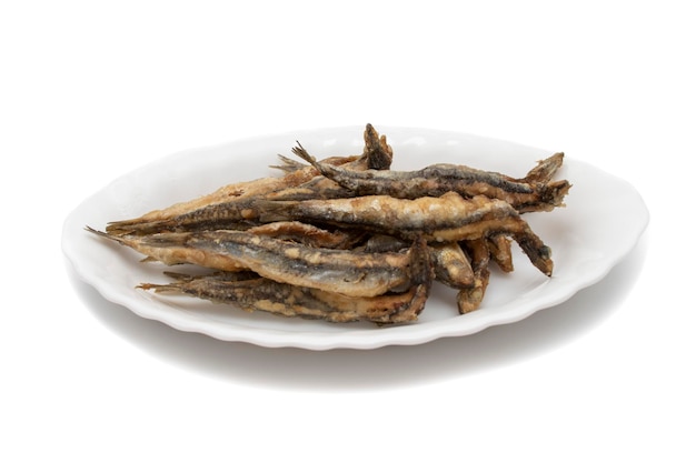 Photo a white plate with fried anchovies, isolated on white background. spanish food concept.