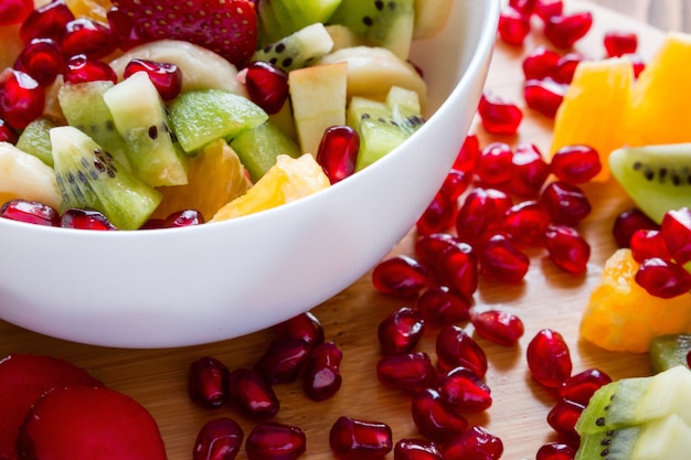 White plate with fruit salad cutting board closeup