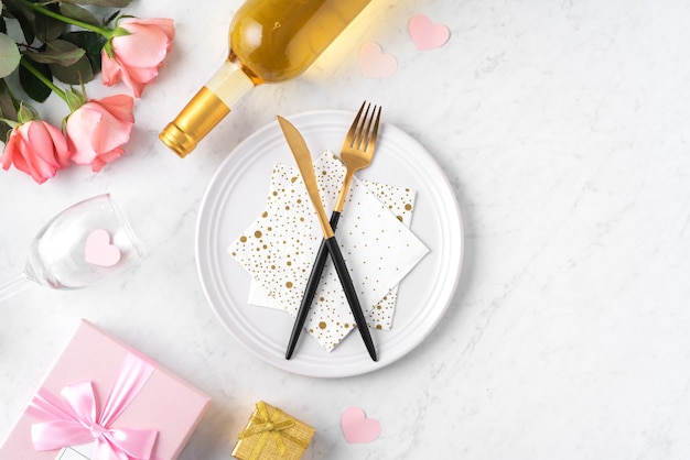 White plate with gift and pink rose flower on marble white table background for Valentine's Day special holiday dating meal concept.