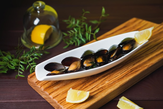 White plate with mussel in sink and lemon slice on wooden desk from above