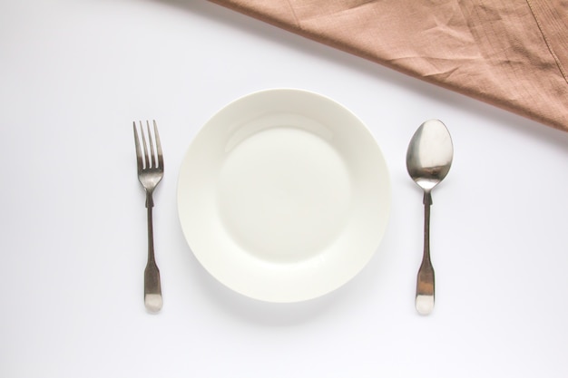 A white plate with silver fork and spoon 