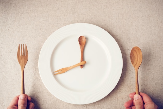 белая тарелка с ложкой и вилкой, концепция прерывистого голодания