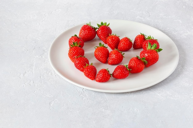 사진 하트 모양의 딸기가 있는 흰색 접시, 발렌타인 데이의 개념, 위쪽 전망, 복사 공간