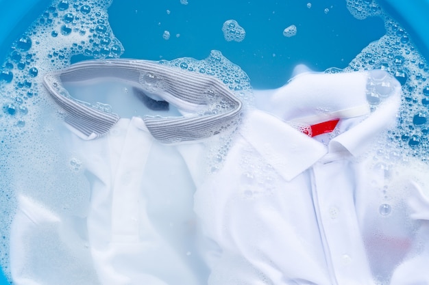 Foto camicie polo bianche immergere in dissoluzione acqua detergente in polvere, lavare i panni.