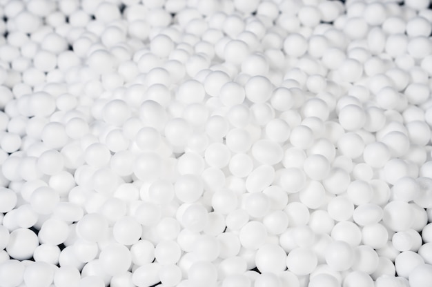 White polystyrene foam beads ball drop from styrofoam machine for fragile stuff packaging box, plastic texture background decoration