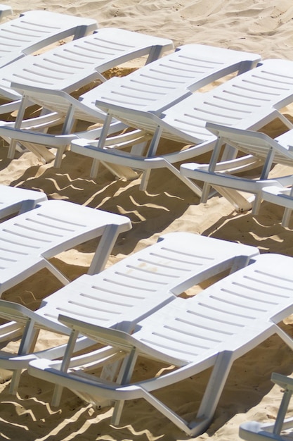 Белые стулья у бассейна на пляже.