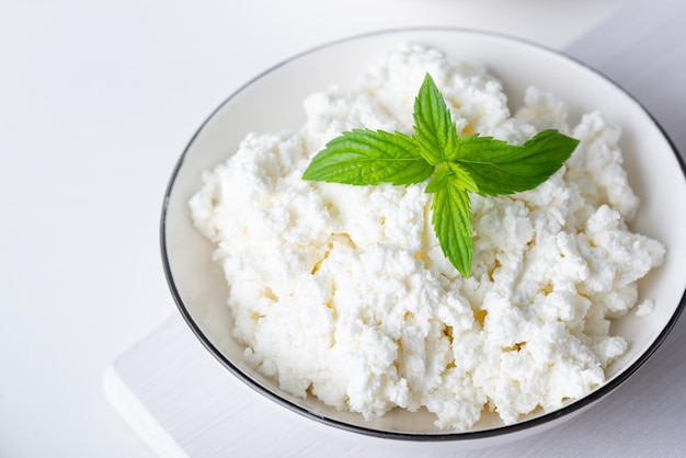 White porcelain bowl with grainy cottage cheese isolated on a white background