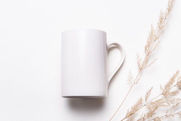 White porcelain coffee cup decorated with dried grass