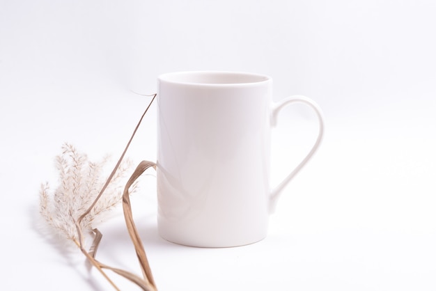 乾いた草で飾られた白い磁器のコーヒーカップ