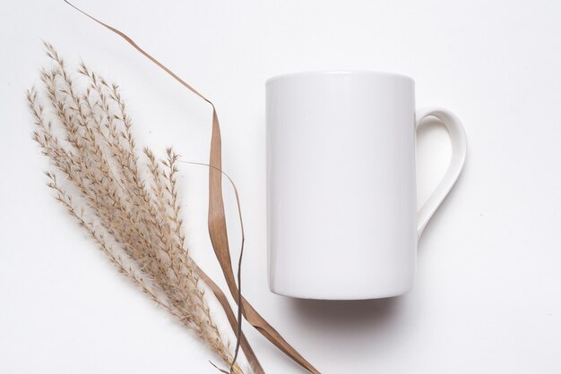 White porcelain coffee cup decorated with dried grass