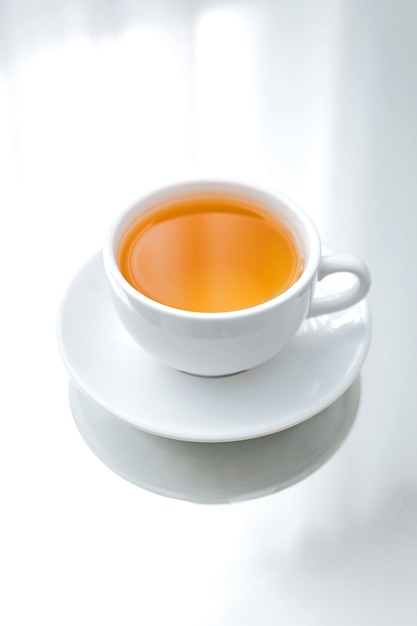 white porcelain cup of green tea on a saucer