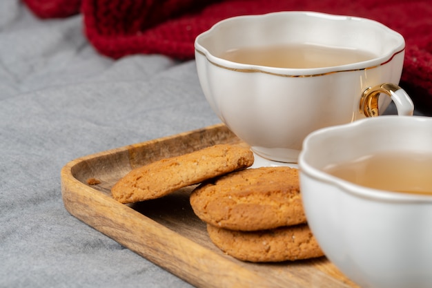 White porcelain cup of tea and oat cookies on a table