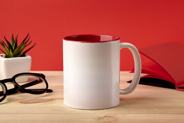 White porcelain mug on wooden desktop next to notepad