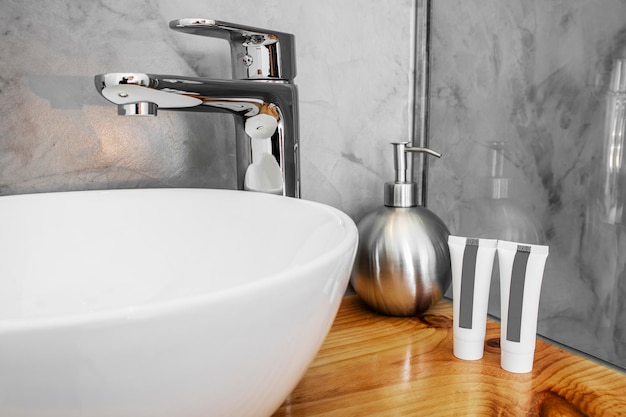 White porcelain sink with soaps on a varnished pine countertop