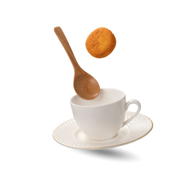 A white porcelain tea cup and a saucer with a wooden spoon levitating on white background.