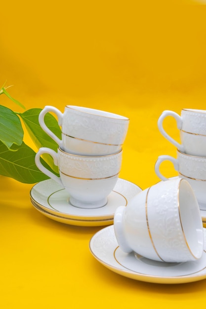 White porcelain tea cup with a golden line decoration on yellow colour background