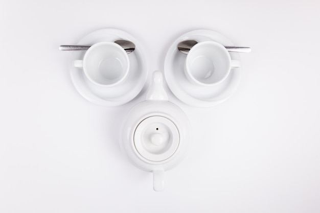 白い磁器のティーポットとコーヒーまたはお茶の空の受け皿のカップ