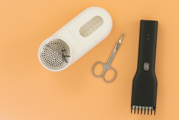 White portable lint remover stainless scissors and hair cutter lays on an yellow background Object Razor Shaving Style Material Product Trim Instrument White Device Fuzz Nail Pedicure