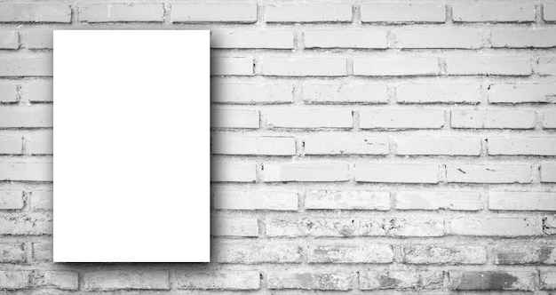 Foto manifesto bianco sul fondo panoramico della parete delle mattonelle del mattone di colore di tono grigio