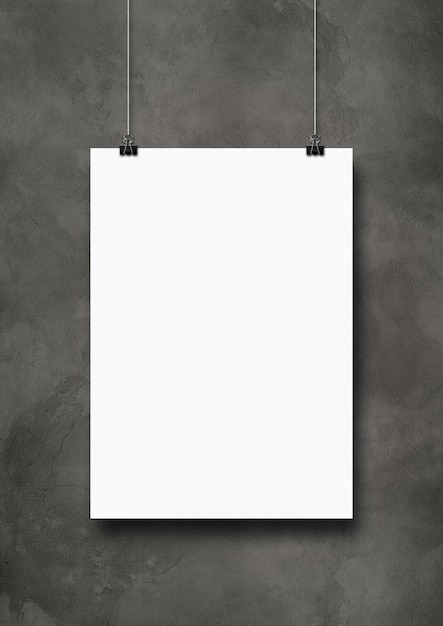 White poster hanging on a dark concrete wall with clips