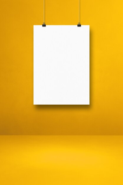 White poster hanging on a yellow wall with clips. Blank mockup template