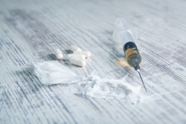 White powder, capsules and syringe on the table