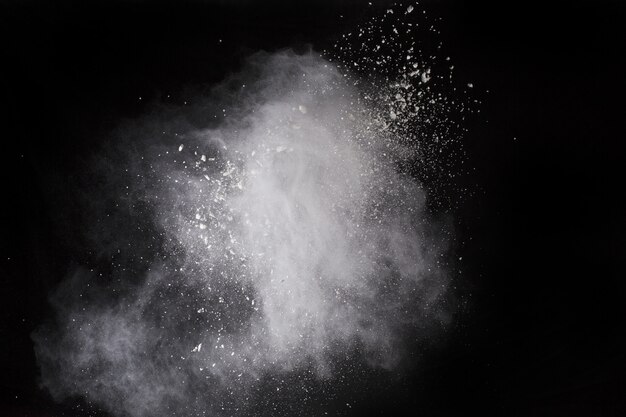 White powder explosion on black background. Colored cloud. Colorful dust explode. 