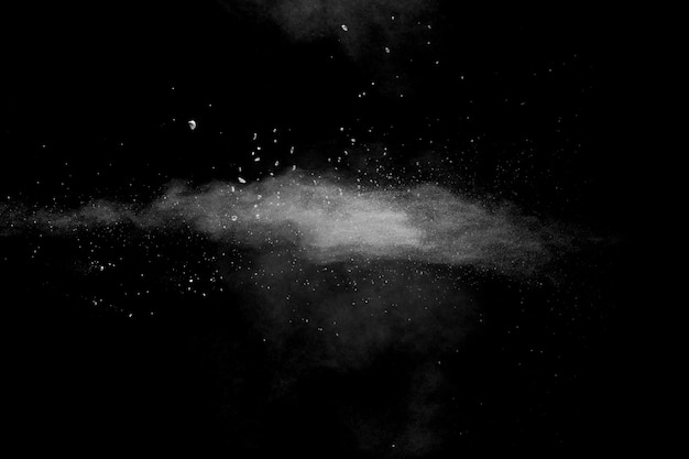 Nuvola bianca di esplosione della polvere contro fondo nero spruzzata bianca delle particelle di polvere.
