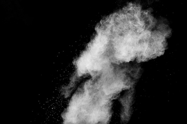 黒の背景に分離された白い粉の爆発。白い粉塵粒子が飛散。