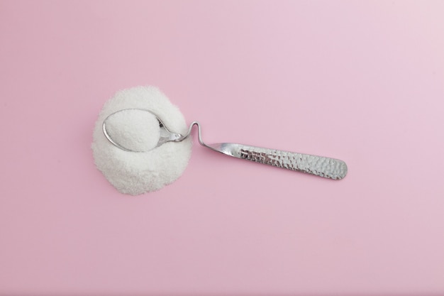 White powder and silver spoon on pink