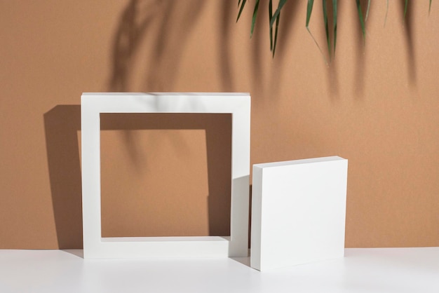 White presentation podiums geometric shapes under palm leaves on a brown background Top view flat lay