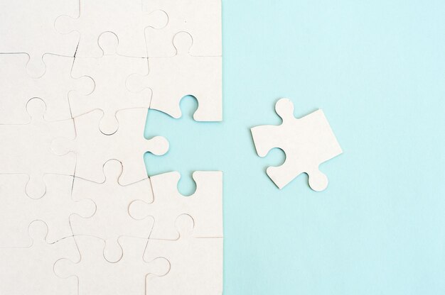 White puzzle background with missing piece on blue background. Top view