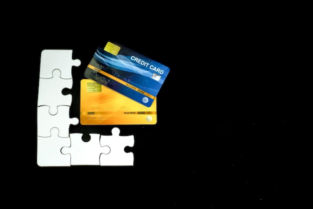 Foto un pezzo di puzzle bianco e una carta di credito su sfondo nero con spazi per il testo