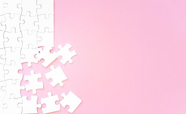 Photo white puzzle pieces on pink background with copyspace