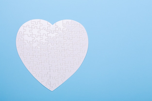 White puzzle in shape of heart on blue 