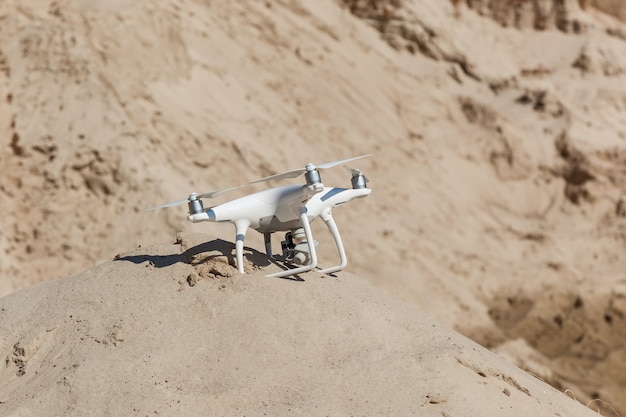 White quadcopter sat down on a sandy hill