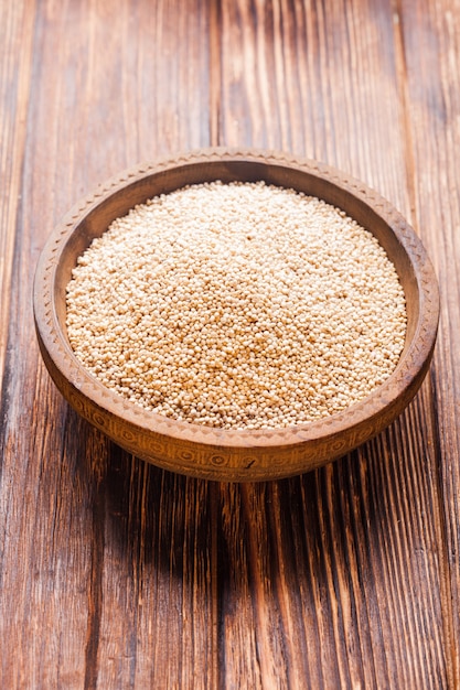White quinoa seeds in a wooden bowl