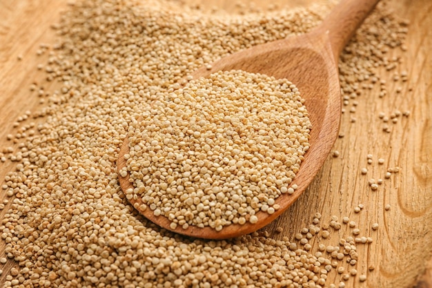 White quinoa in spoon on wooden background