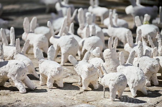 White rabbit statues made of plaster at outdoor art exhibition funny white hares on street