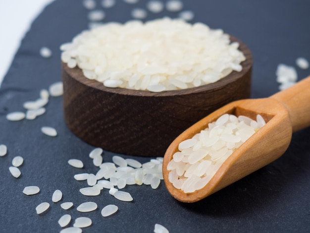 Белый сырой рис в миске и крупный план деревянного совка
