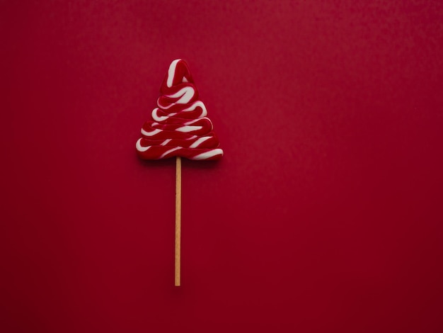 White red candy in the form of a Christmas tree on a red background