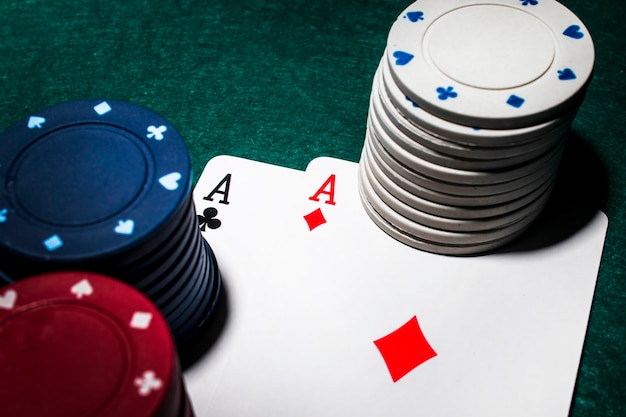 Photo white and red casino chip stack over the diamond and club aces