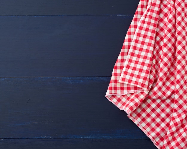 White and red checkered kitchen towel on a blue wooden surface