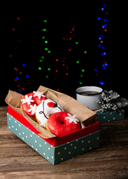 white and red donuts decorated for christmas in green box with backlights