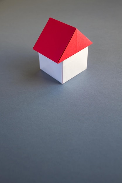 White and red paper house origami isolated on grey background