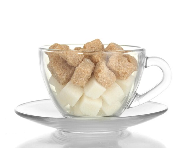 Photo white refined sugar and lump brown cane sugar cubes in glass cup isolated on white