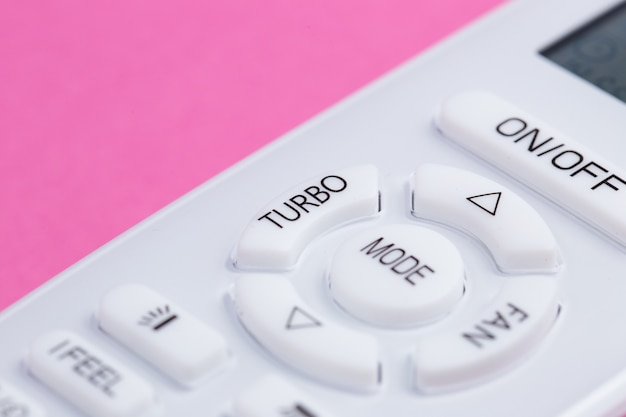 White remote control for air conditioning on a pink background close-up