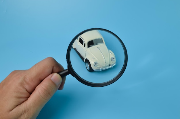 White retro car model and magnifying glass Find a car and car search concept